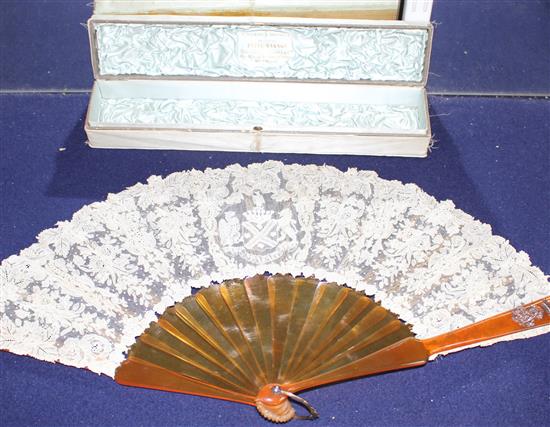 A Maison Patte-Hannot boxed lacework fan, with simulated amber sticks, inset with a rose diamond set crowned monogram, the lacework wit